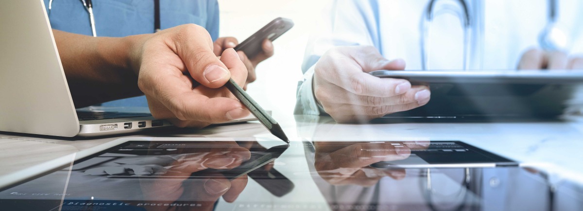 Two people looking at laptops and tablets only showing their hands